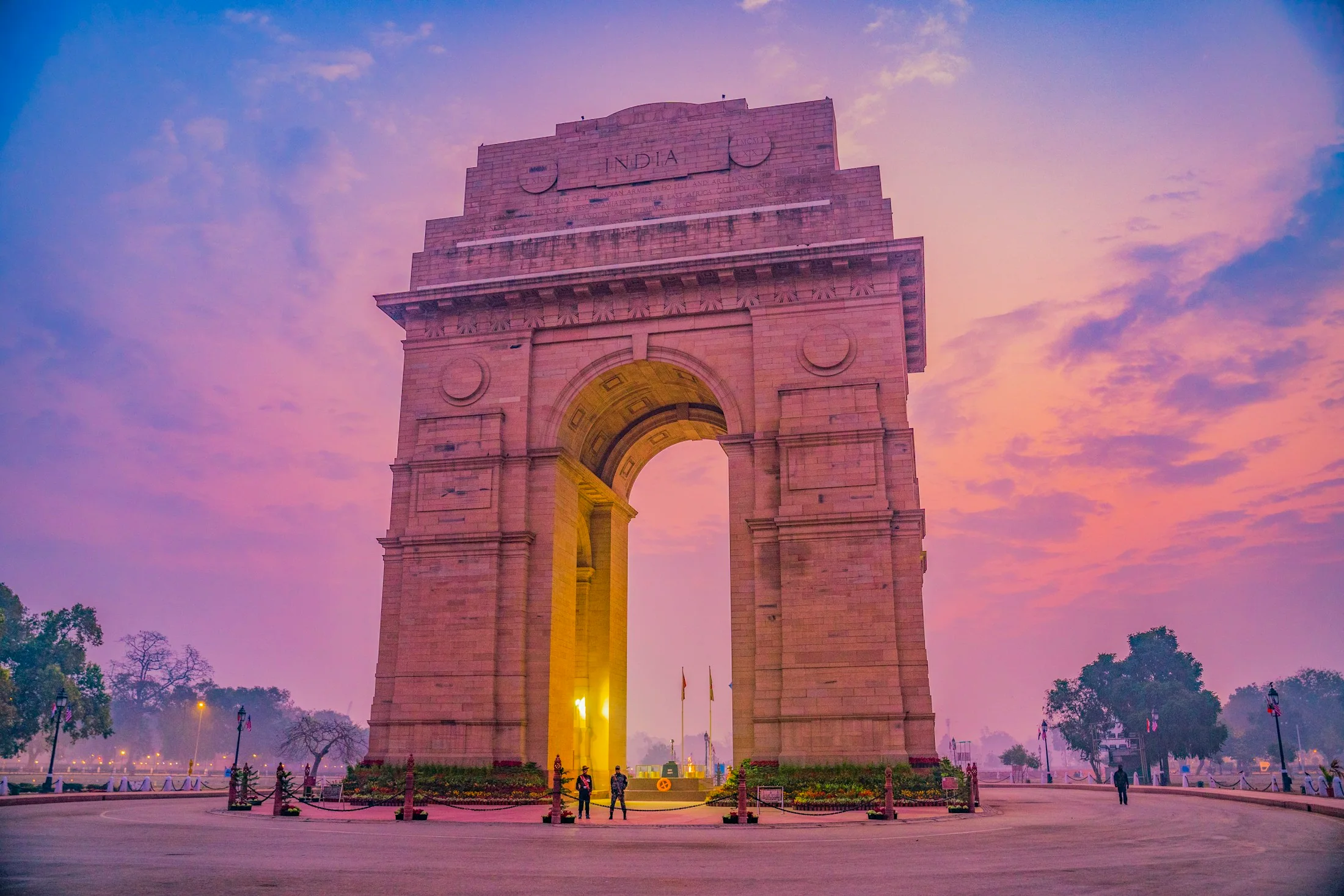India Gate standing floodlit against a violet dusk sky at the end of the Rajpath in New Delhi