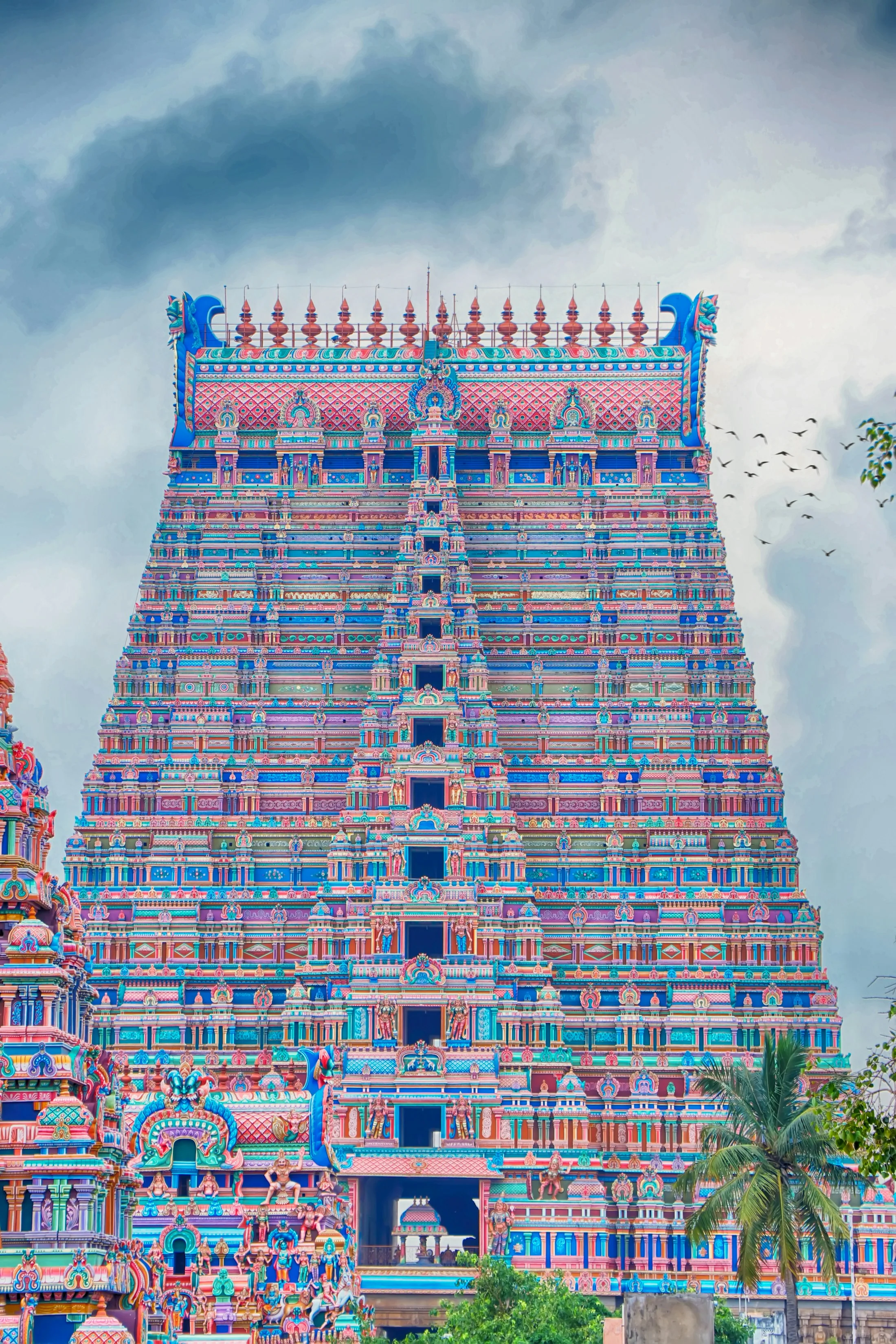 A painted temple gopuram rising above the rooftops of Madurai in early light