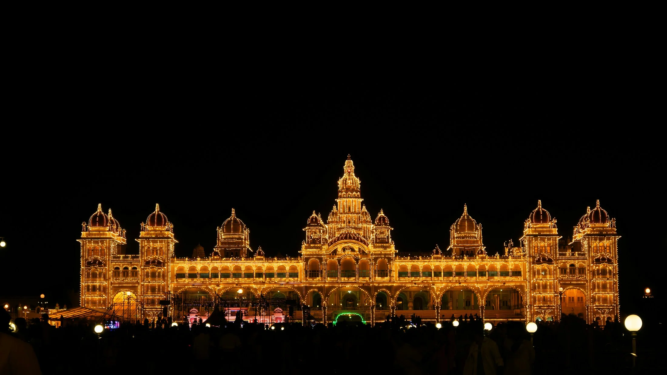 Mysore Palace at night with its every outline traced in warm bulbs against a dark sky
