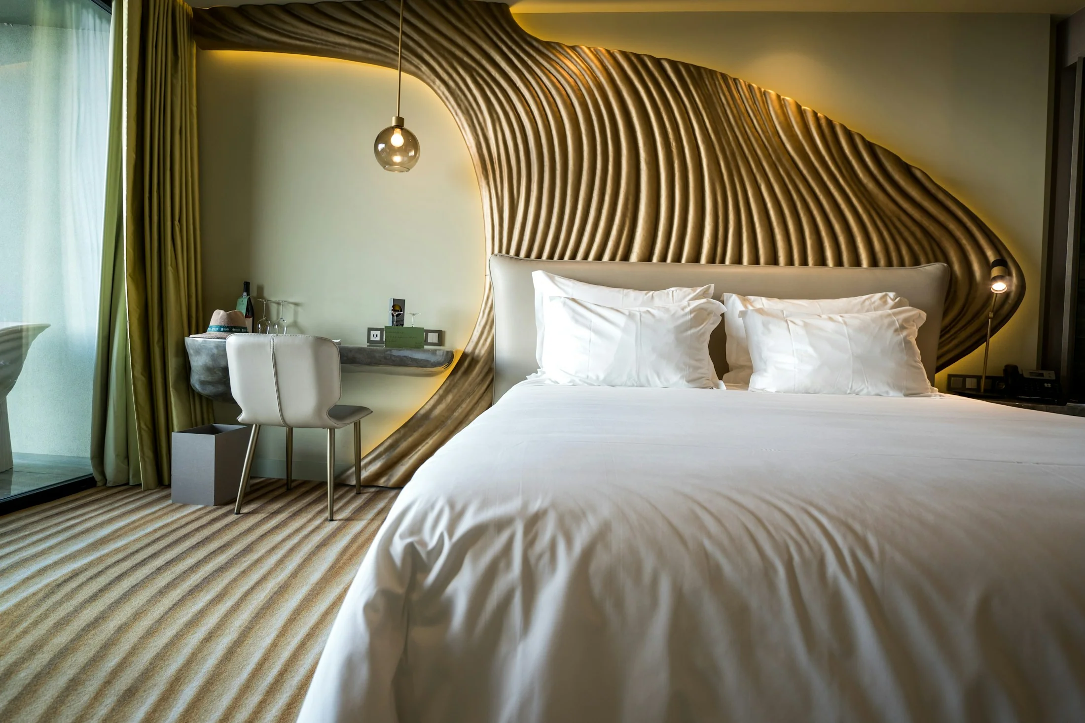A premium hotel bedroom with a fluted timber headboard, crisp linen and low warm lighting